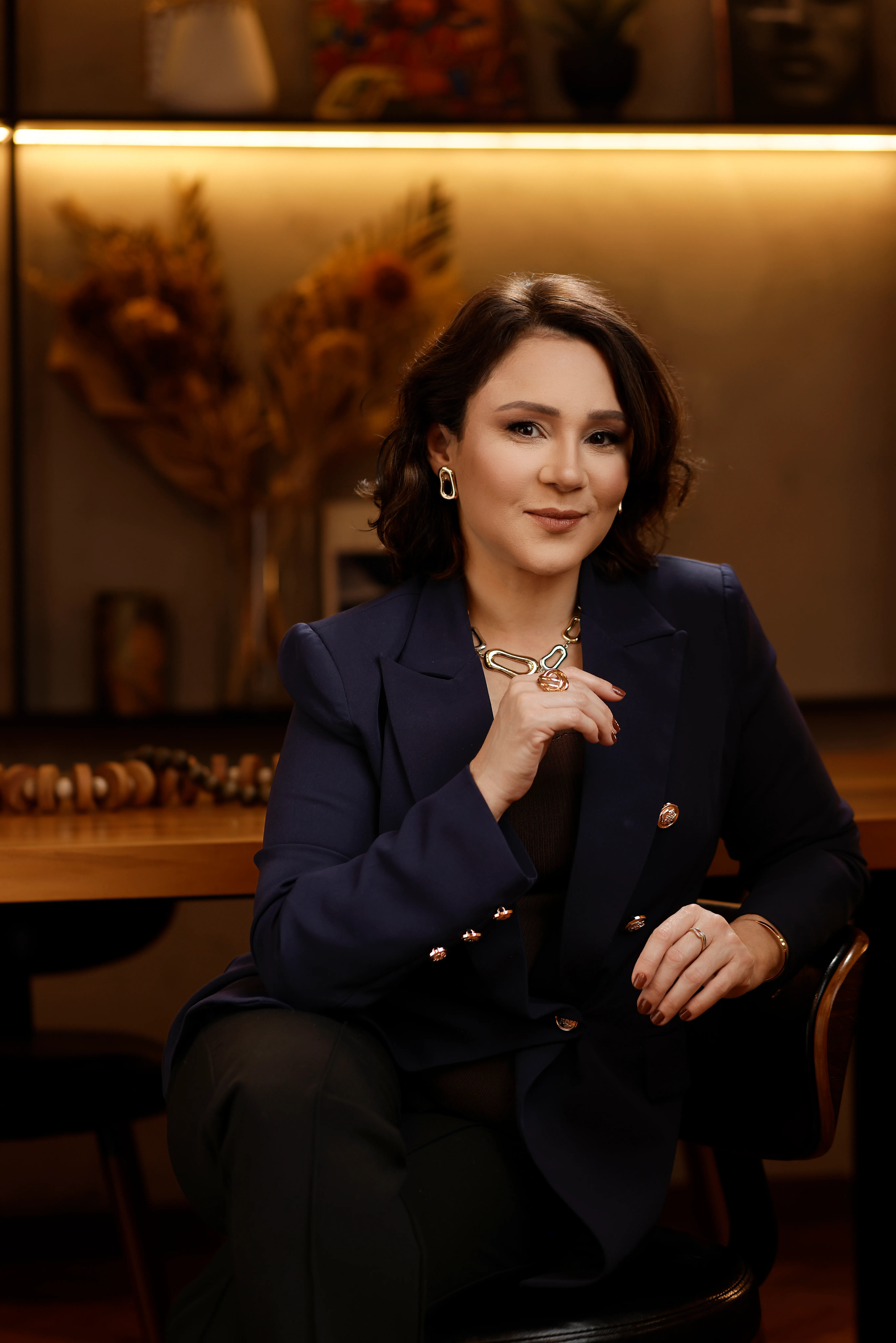 Retrato de Katiuscia Silva, de blazer azul-marinho, com a mão no queixo e olhar sério.